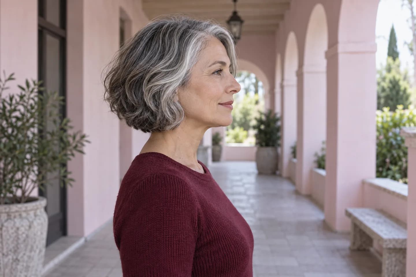 Independent side-profile portrait of an adult woman with a silver and charcoal jaw-length waved bob in a pink walkway
