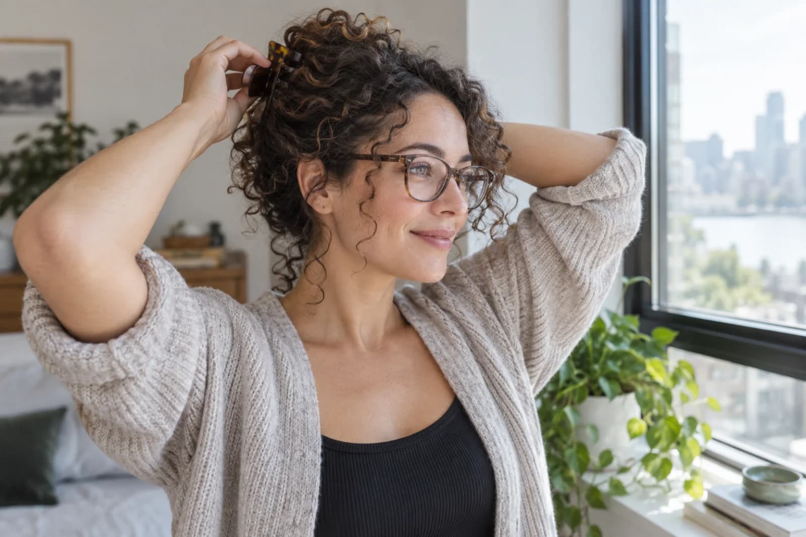 Adult with curly hair and glasses loosely clipping hair away from the temples