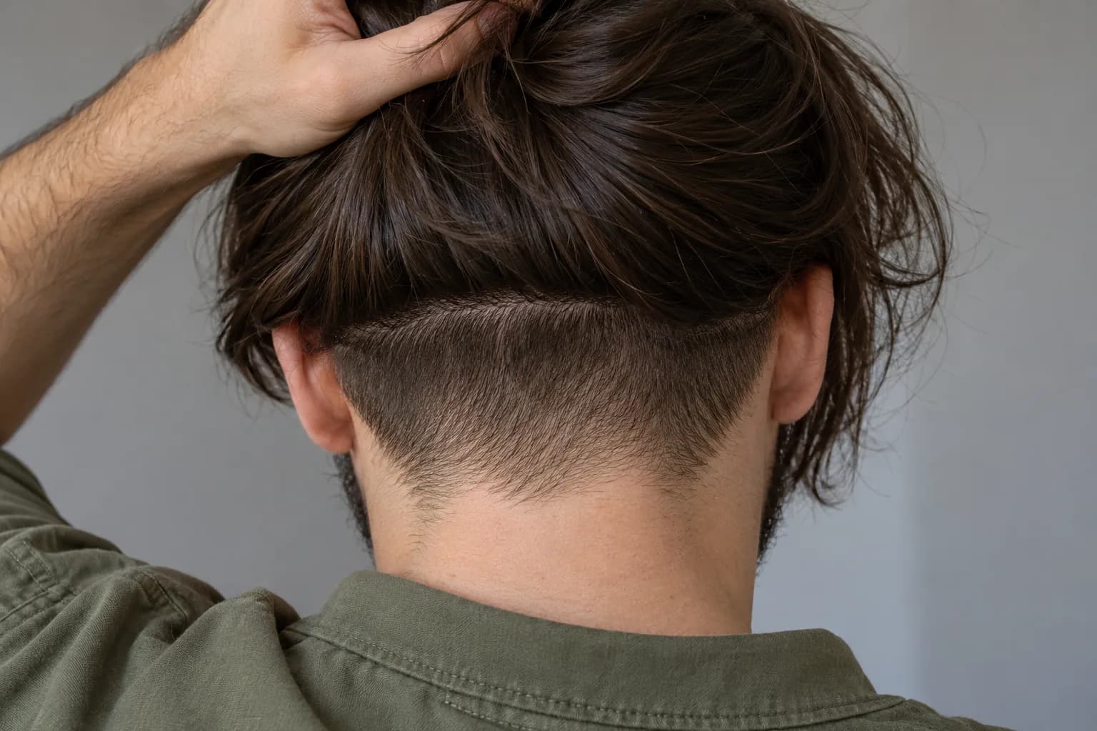 Close rear view of long dark hair held up above a narrow low nape undercut