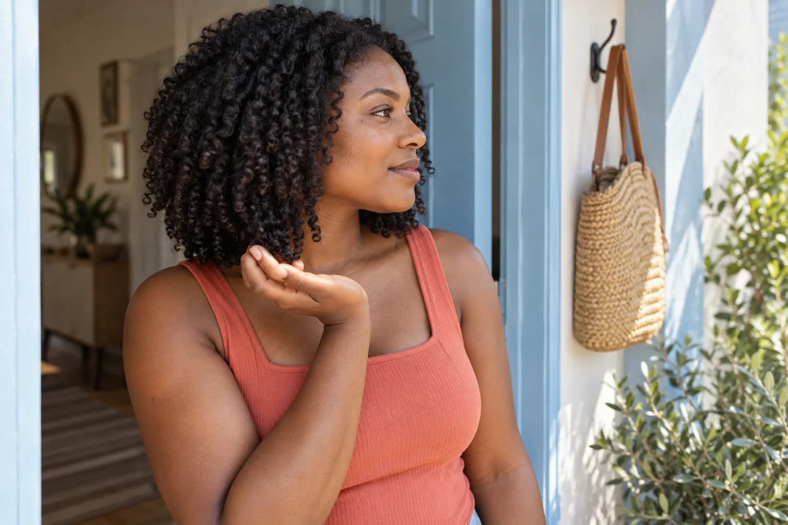 Adult Black woman supporting a lower coil without stretching it at a pale blue doorway