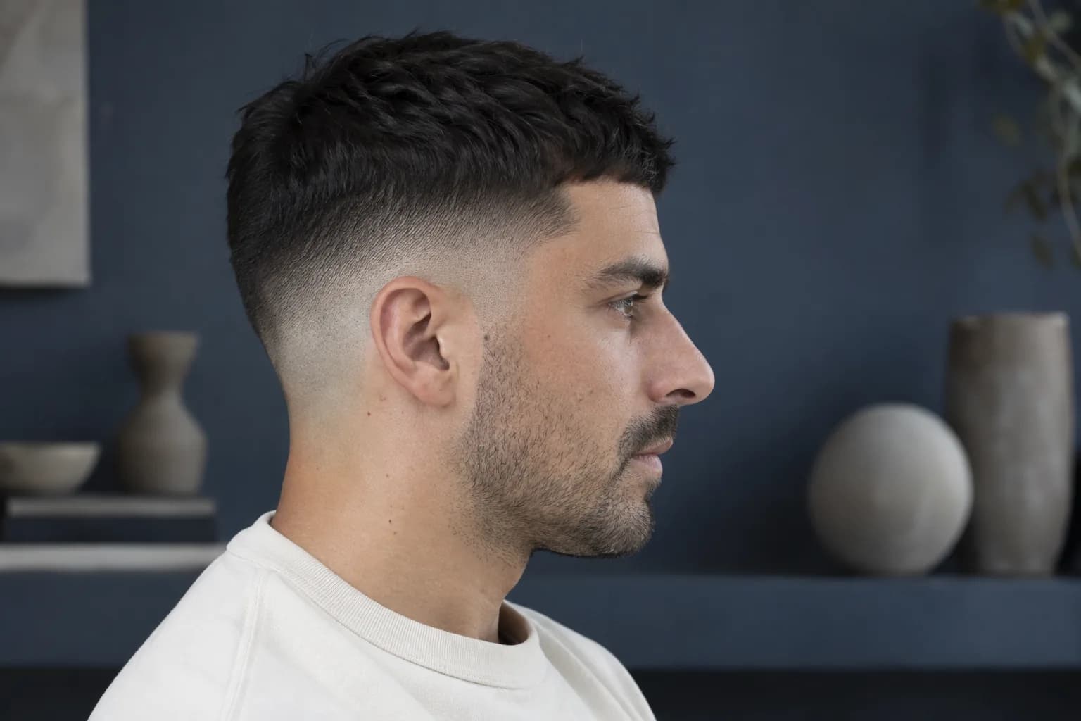 Side profile of an adult man with a low fade showing the short base, gradual blend and dark hair retained above the ear
